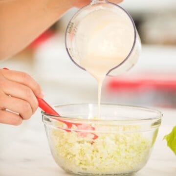 coleslaw dressing pouring into cabbage.