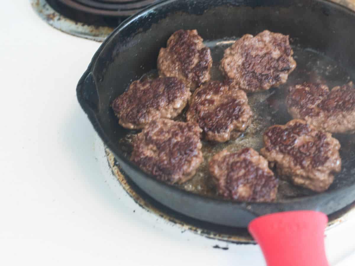 beef frying in a cast iron pan