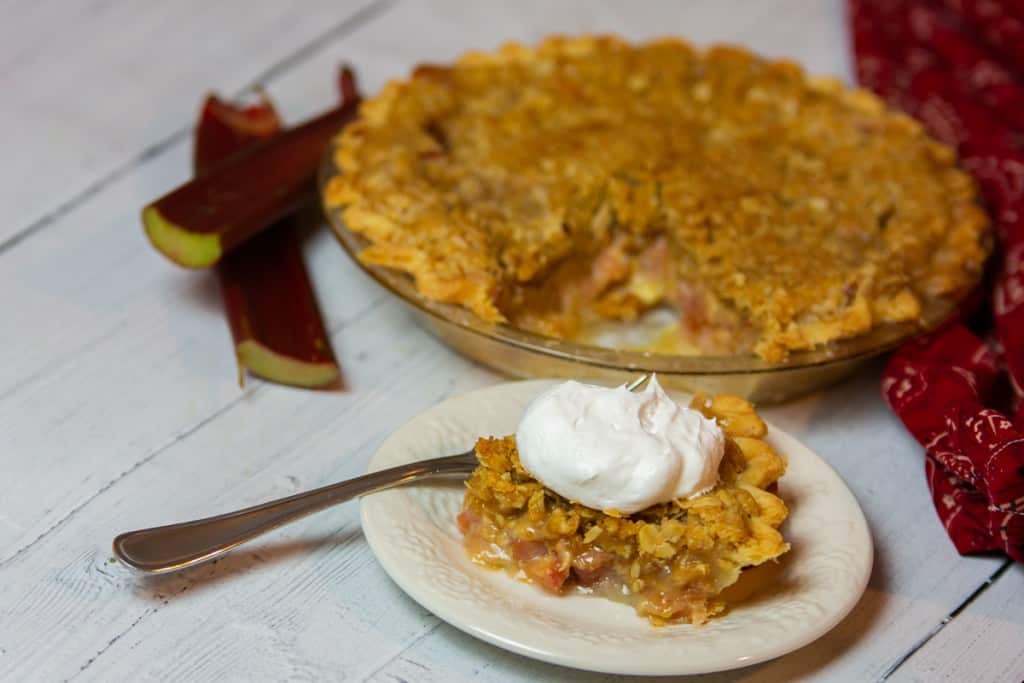 Slice of rhubarb pie on a plate, with whipped cream