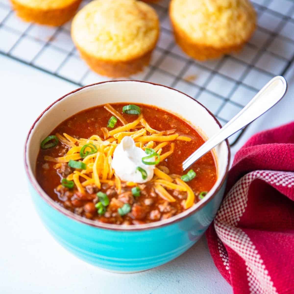 blue bowl with chili soup and topped with cheese and sour cream