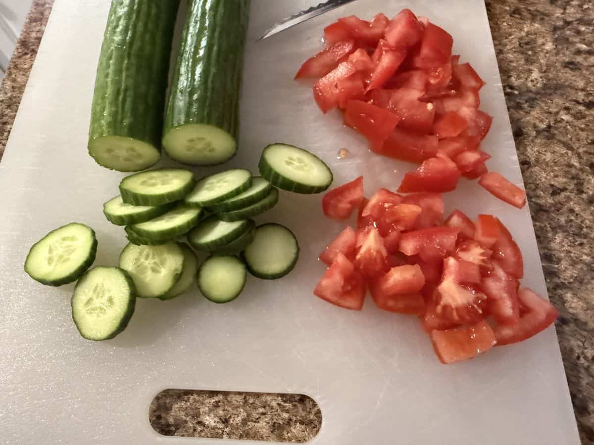 sliced cucumber and tomato on a cutting board.