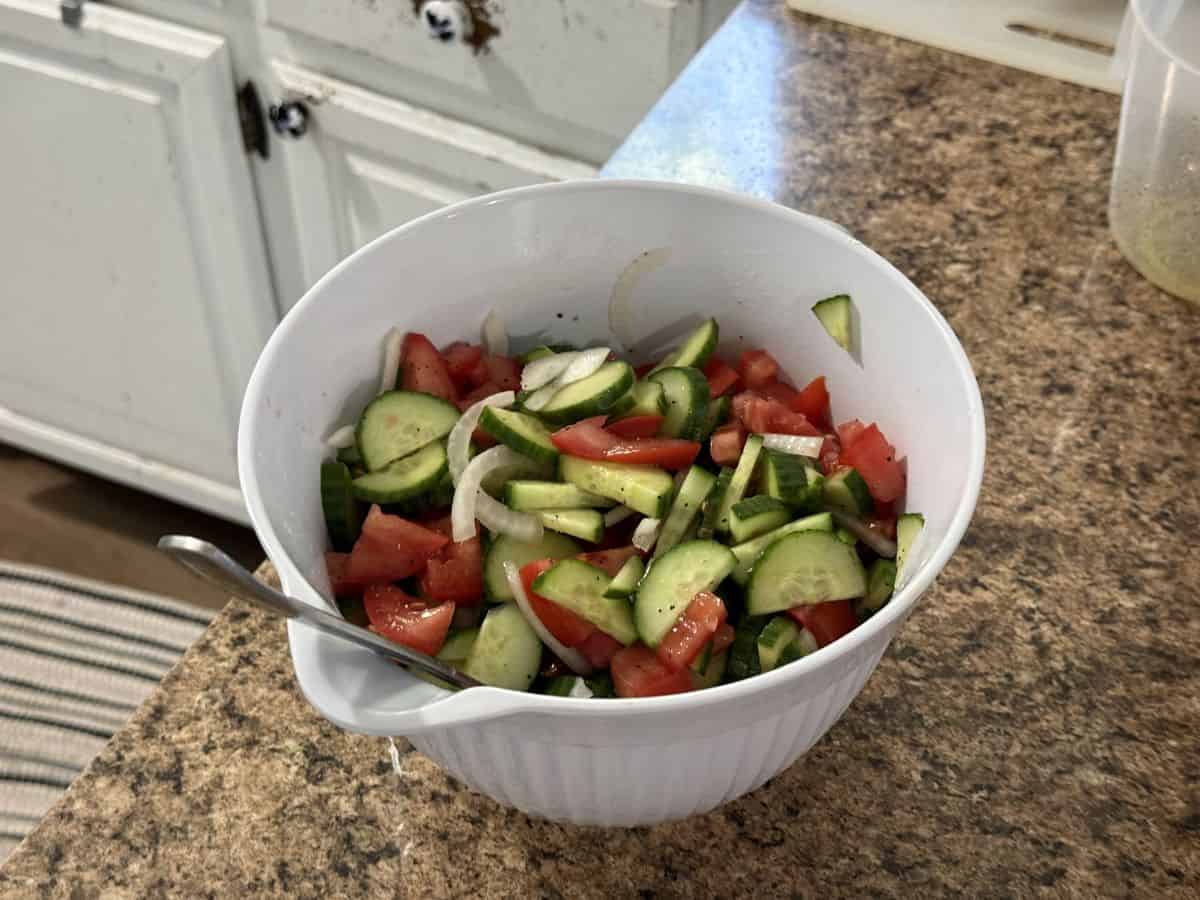 cucumber tomato salad in white bowl.