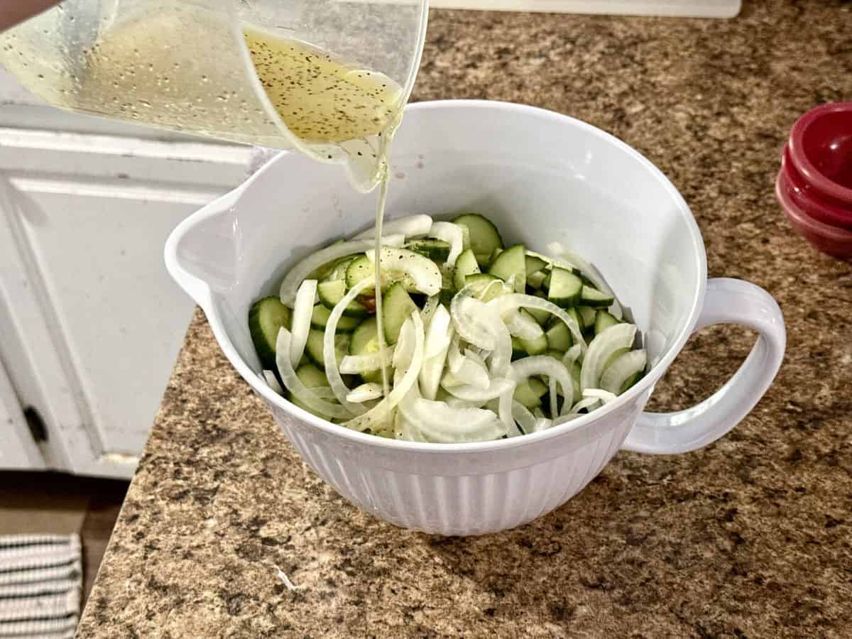 salad dressing pouring over cucumber salad.