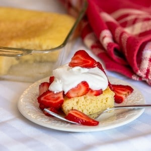 pound cake on a plate, with strawberries and whipped cream on top