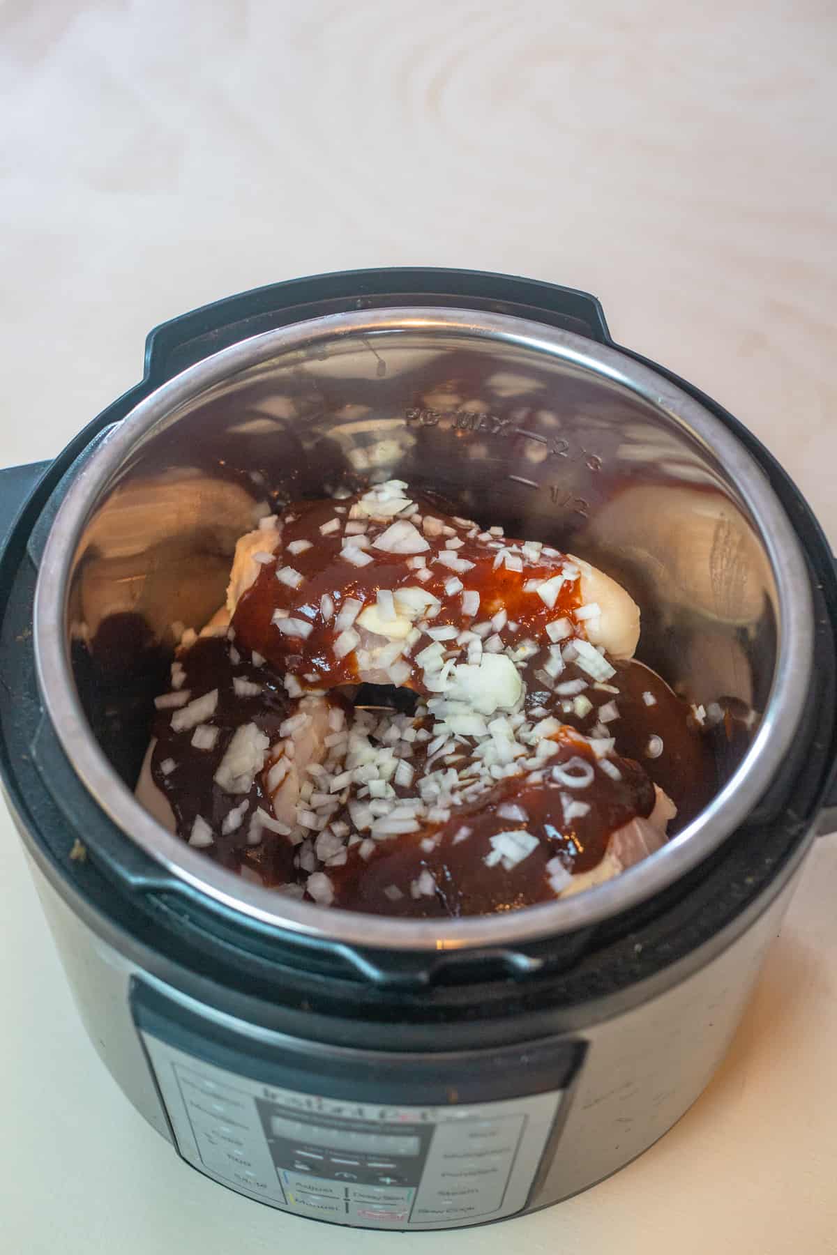 chicken in pot with bbq sauce and onion on top