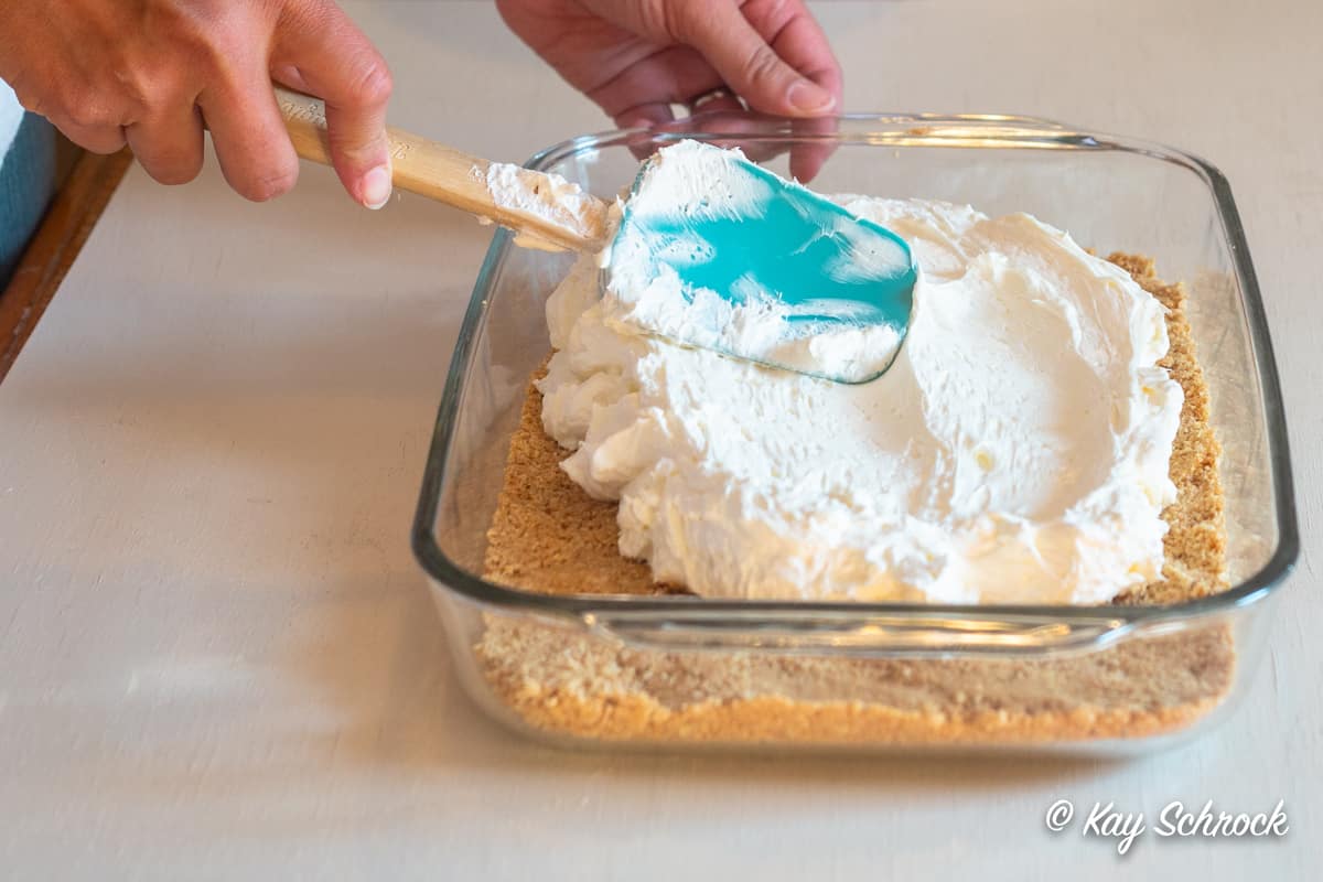 cheesecake filling being spread onto graham crust