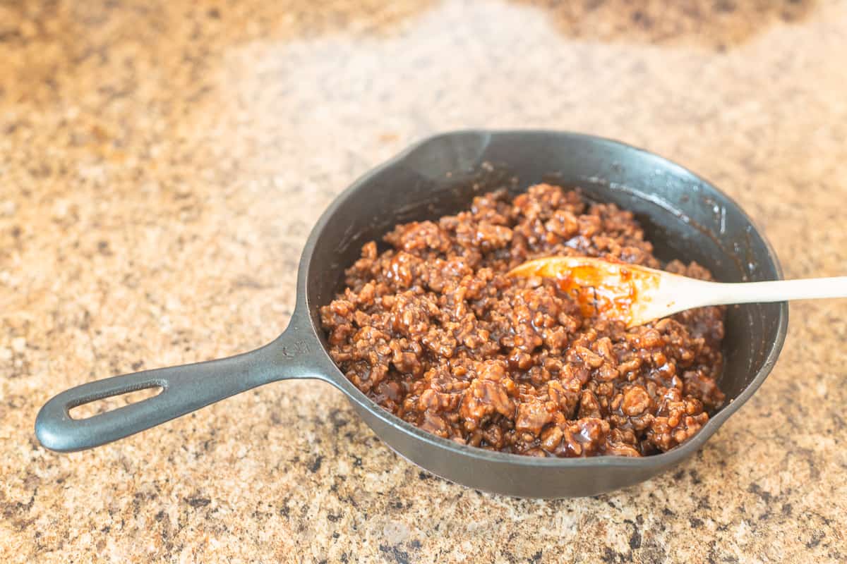 cast iron skillet with cooked beef and bbq sauce