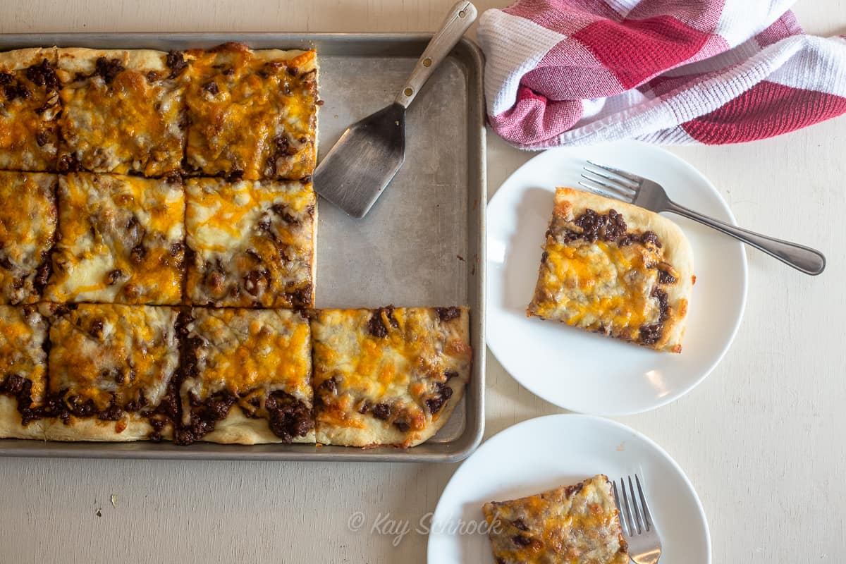 large pan of bbq beef pizza, cut in squares and two pieces on plates