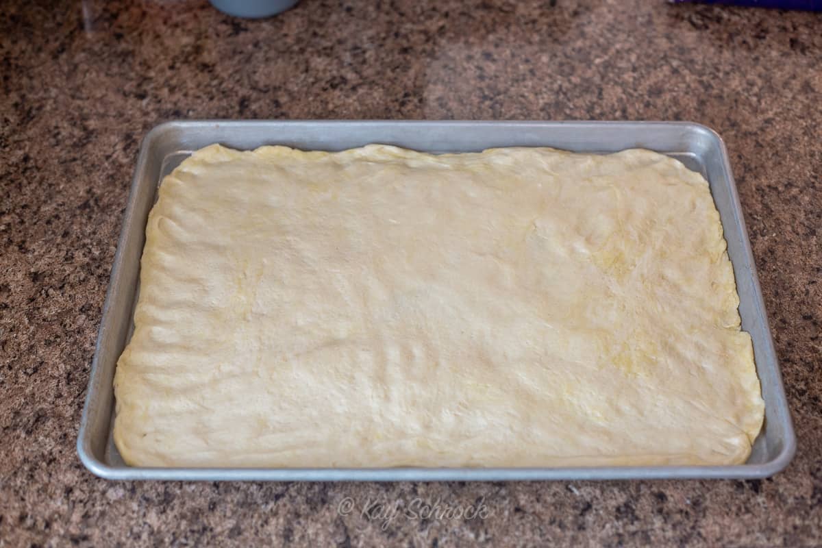 large pan with raw pizza crust on it