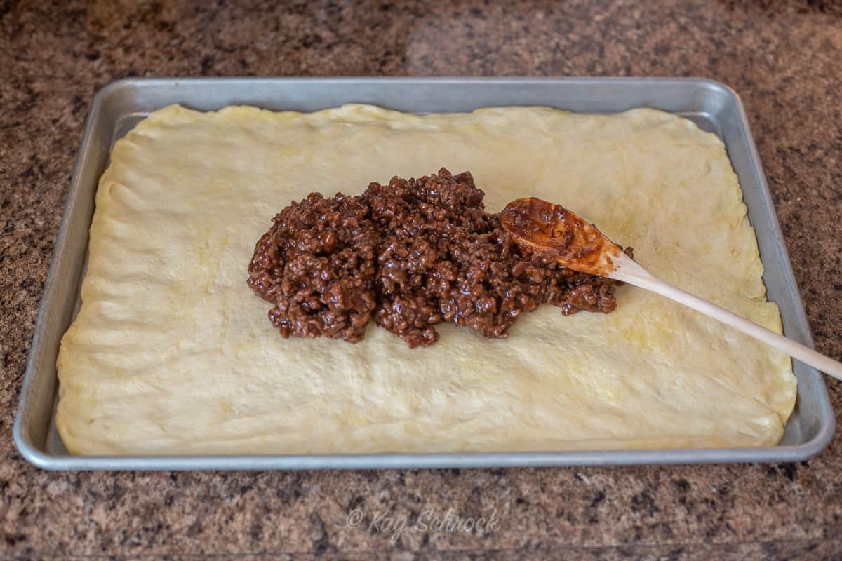 large pan with pizza crust and a  dollop of ground beef mixture