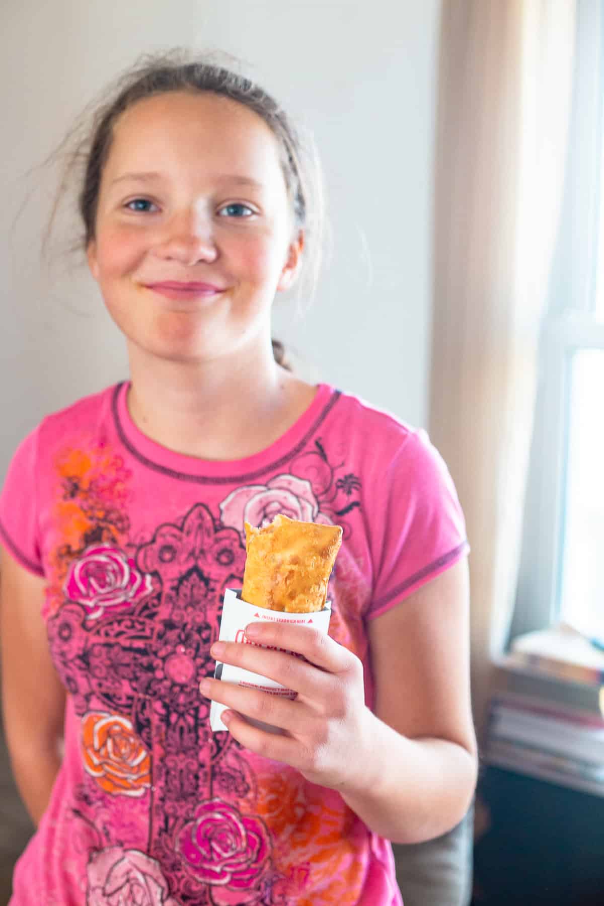 girl in pink shirt holding hot pocket