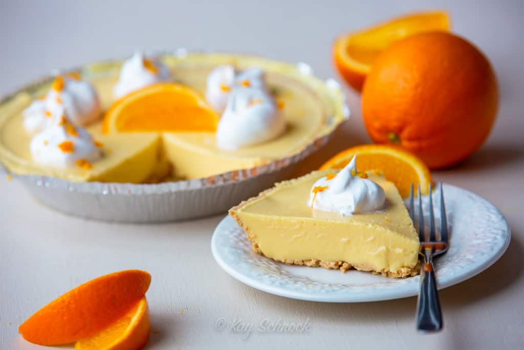 orange mousse pie sliced on plate surrounded with oranges