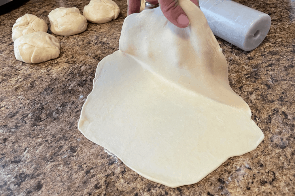 hand lifting flour tortilla from counter