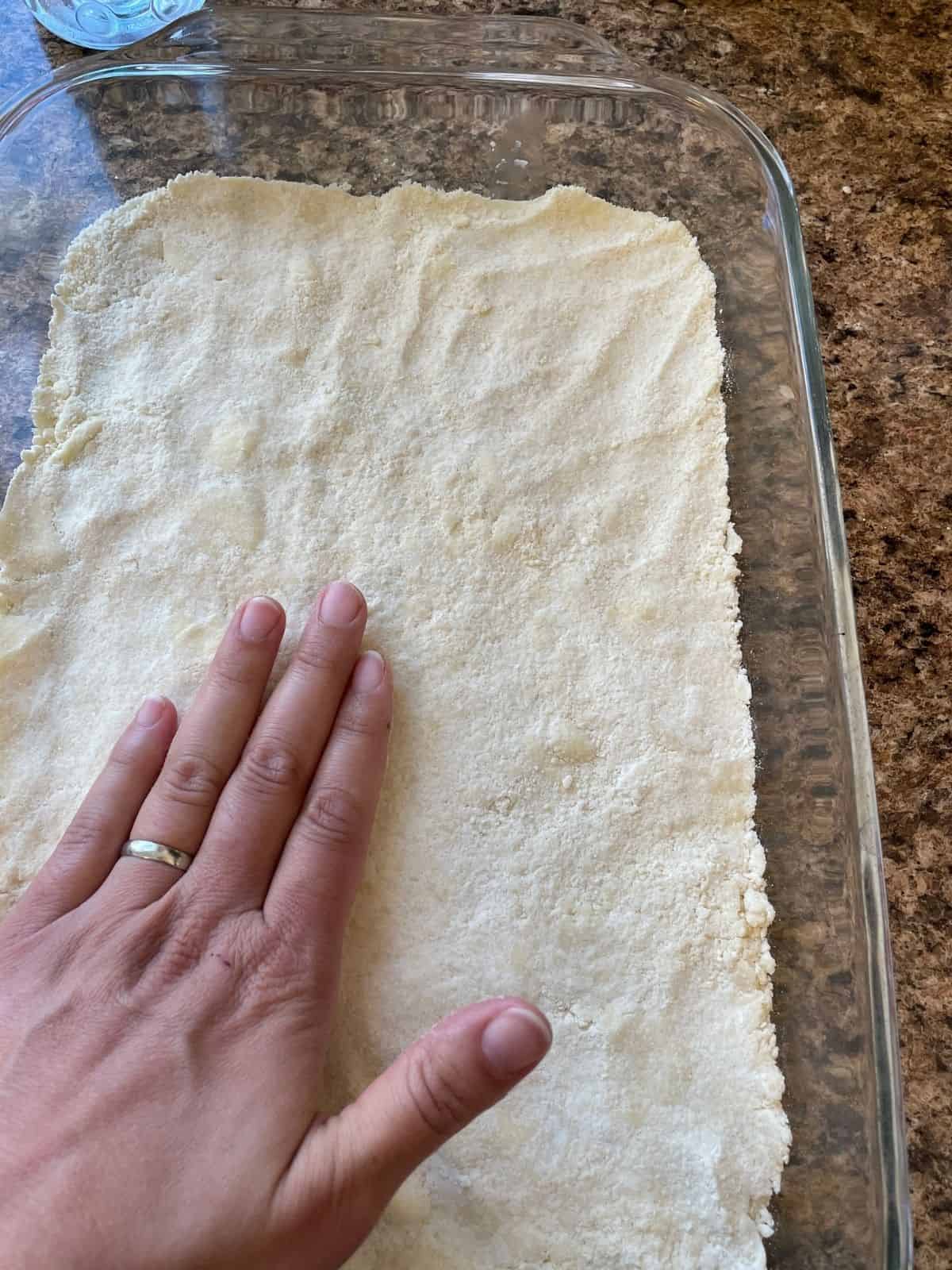 hand patting crust into pan