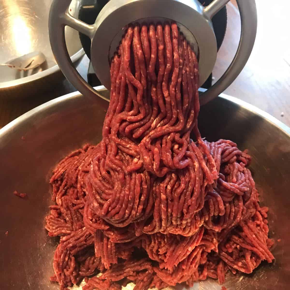 venison meat coming out of a grinder