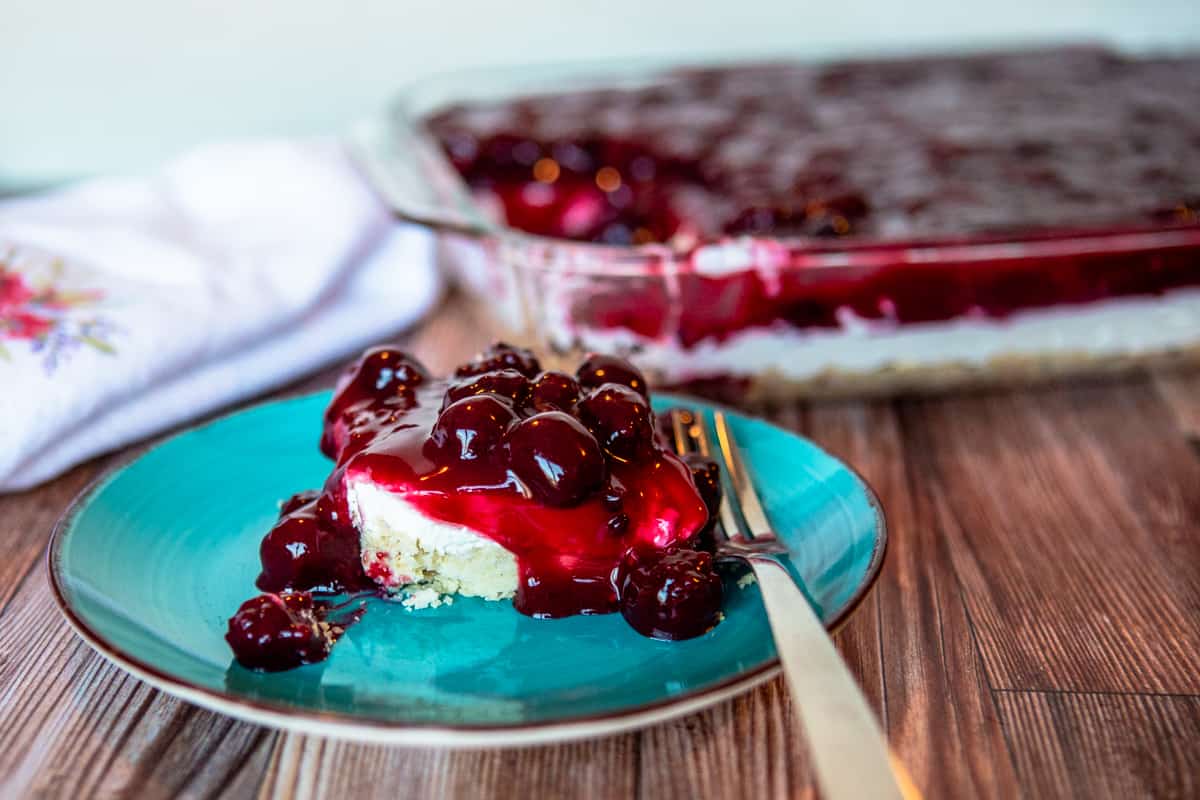 Blackberry Delight in a 9x13 pan with a serving on a blue plate