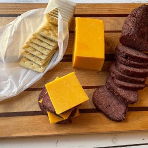 venison summer sausage, cheese and crackers on a serving board
