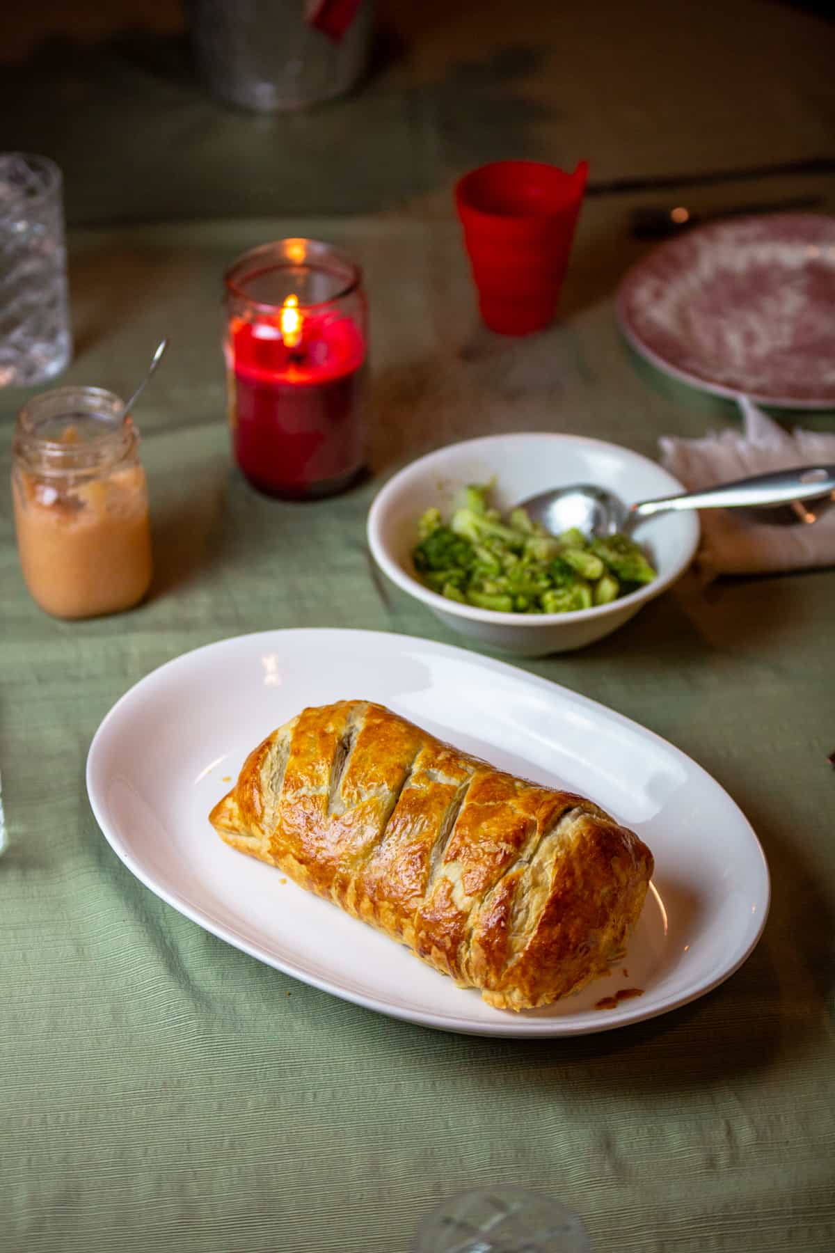 venison wellington on a white platter on table with meal