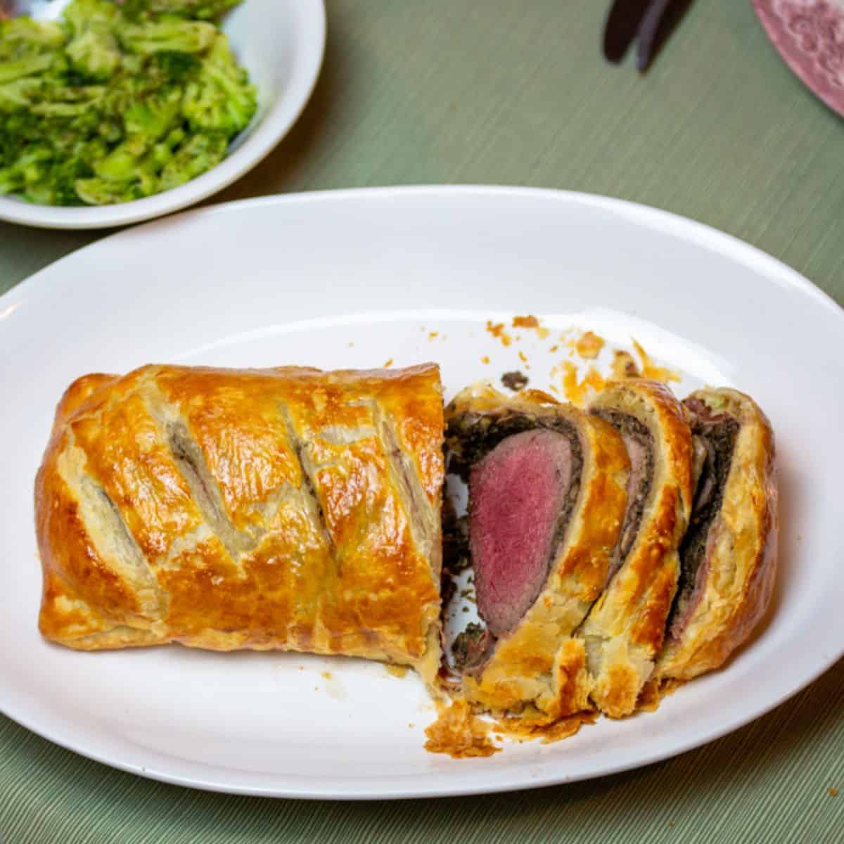 venison wellington sliced on a white platter