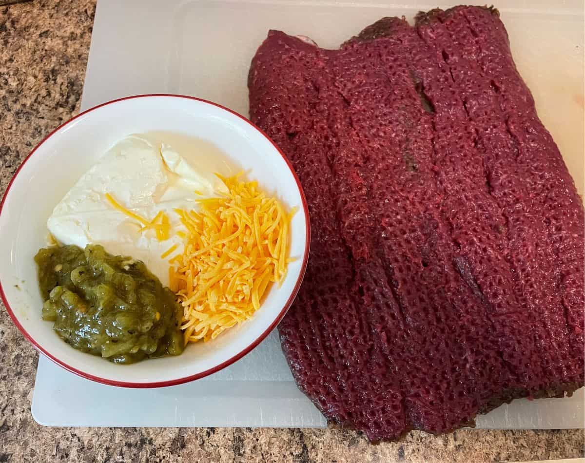 raw elk loin with bowl of cream cheese stuffing next to it