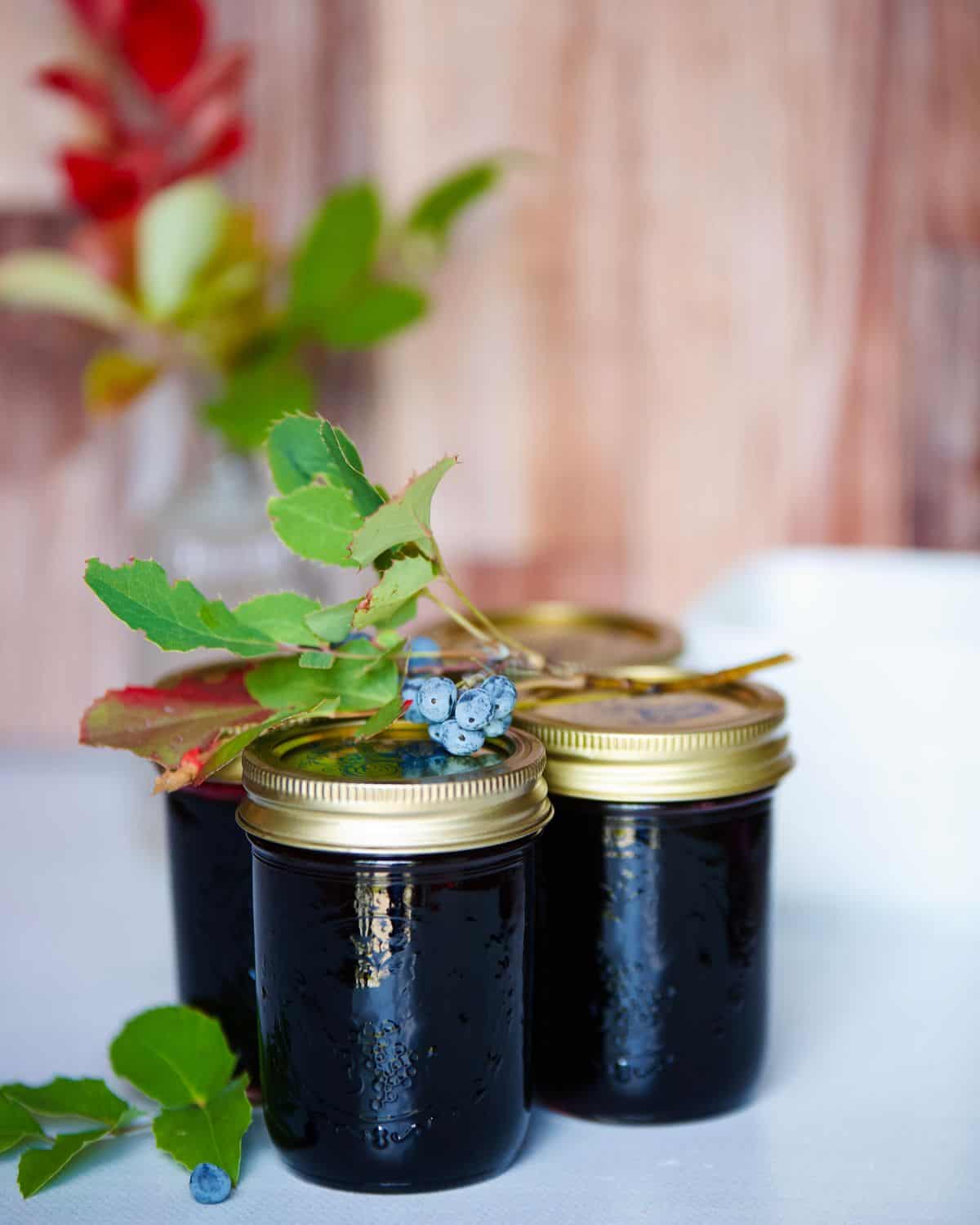 Oregon grape jelly in jars with leaves and berries