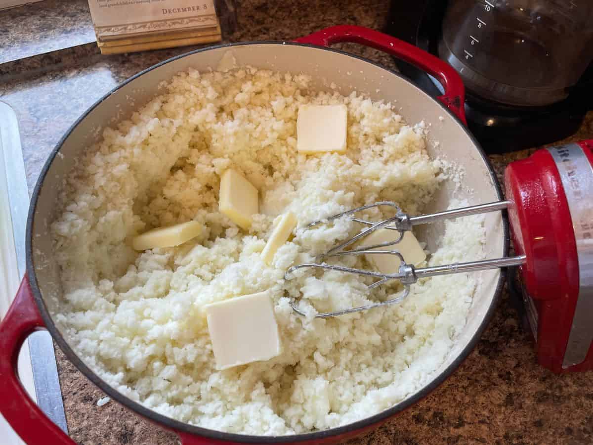 pats of butter lying on a kettle of mashed potatoes
